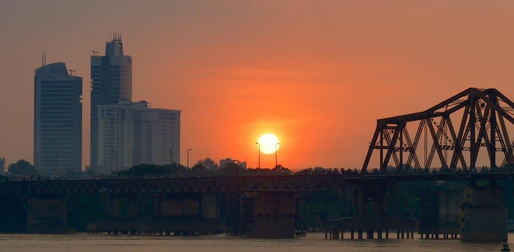 Sunset over a bridge spanning the river to the city skyline, representing bridge financing crossing to permanent capital