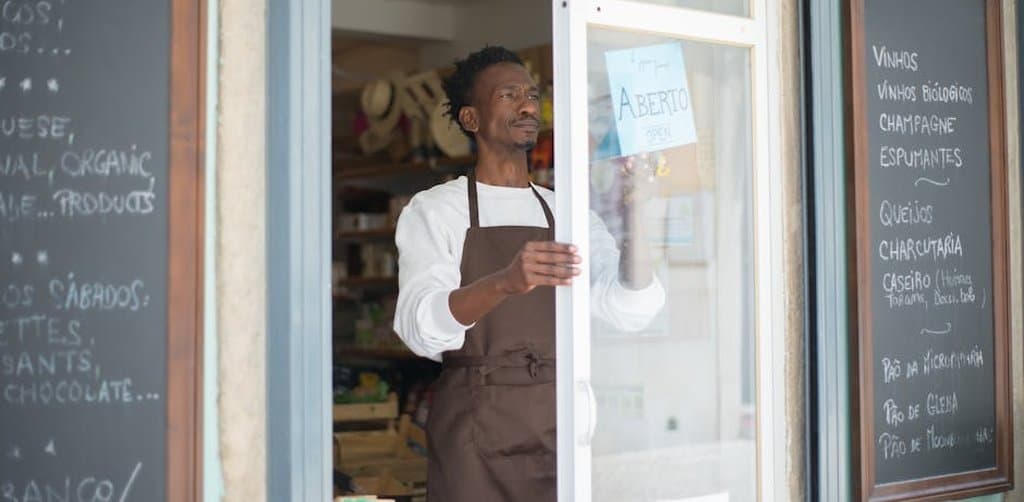 small business owner at storefront after closing a business acquisition loan