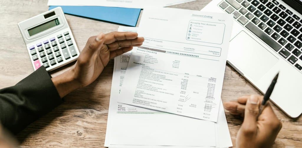 Reviewing bank statements and cash flow with a calculator to evaluate consolidating business debt