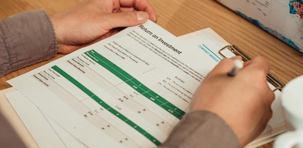 Hand reviewing a return on investment report with a pen, the kind of analysis behind every credible business investment decision