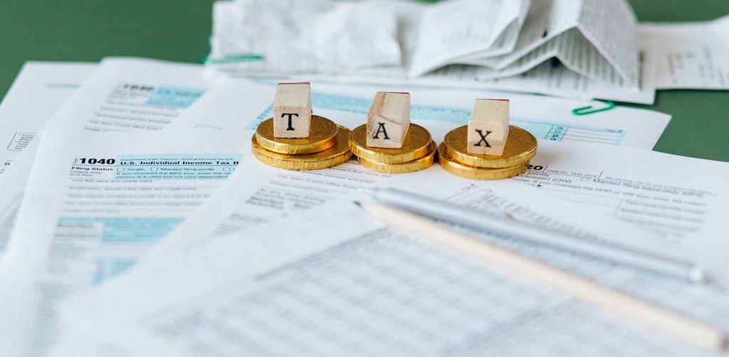 IRS 1040 tax form with coins and the word TAX on wooden blocks, representing an involuntary tax lien on a business