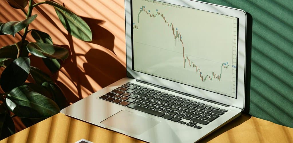 Laptop screen displaying a financial chart next to a printed finance report on a sunlit desk, the data picture that drives cash flow lending decisions