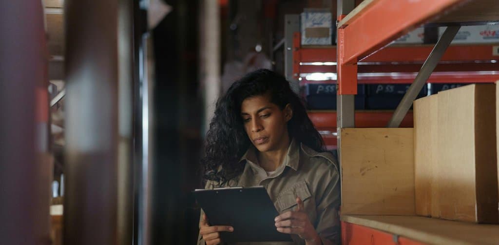 Warehouse employee taking inventory with a clipboard, the kind of ongoing collateral monitoring that defines asset-based lending
