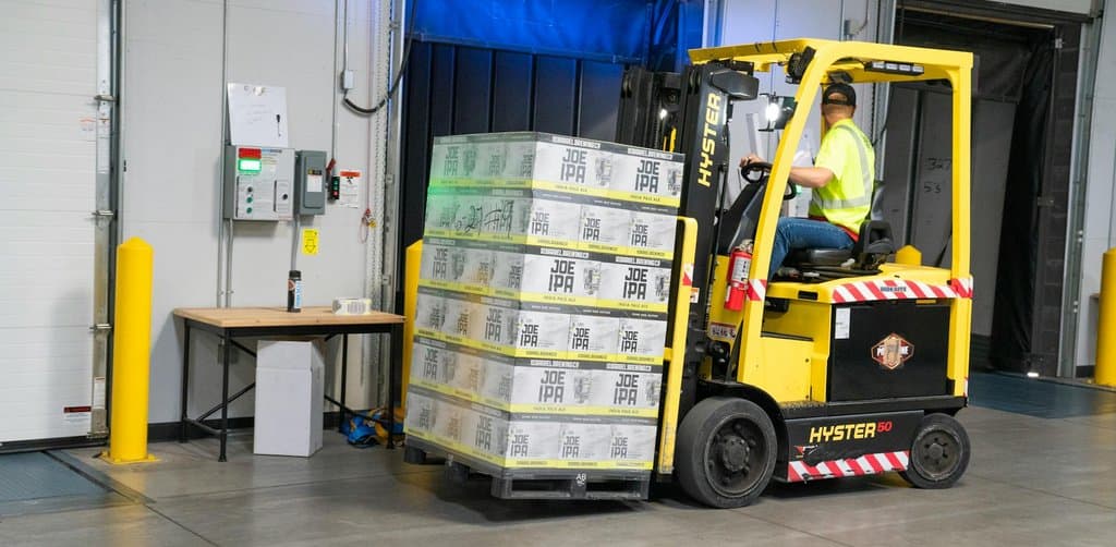 Forklift moving stacked pallets of inventory in a warehouse, a common business asset class pledged under collateral agreements