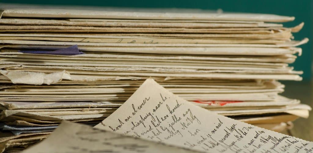 Stack of aged paper notes and a handwritten letter resting on a desk, the kind of seasoned promissory note portfolio that earns the tightest discount rates from professional business note buyers