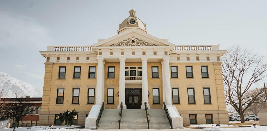 Historic yellow-brick county courthouse with white columns and dome clock against snowy ground, the kind of state and county records office where a buyer pulls public lien filings when learning how to check for liens before buying a business
