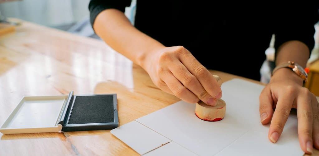 Hand pressing a wooden release stamp with red ink onto paper, the visual signal of how to remove a business lien from the public record