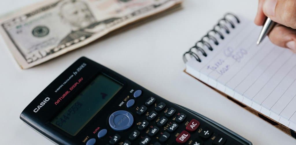 Calculator, cash, and a notebook with handwritten loan terms, the practical math behind a small-business investment decision