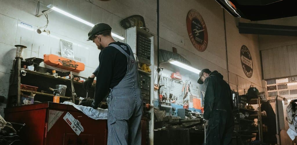 Two mechanics working in a neighborhood auto repair garage, the kind of small business that real investors put real capital into
